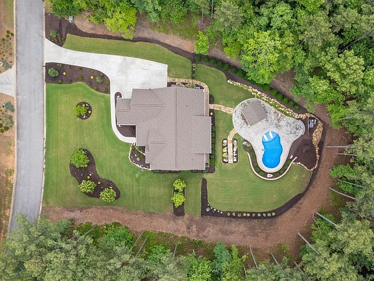 Overhead aerial of the 2.45-acre property at 107 Cedar Bluff Ct showing the farmhouse roofline, the kidney-shaped pool, the manicured lawn, and the pine forest that wraps the lot